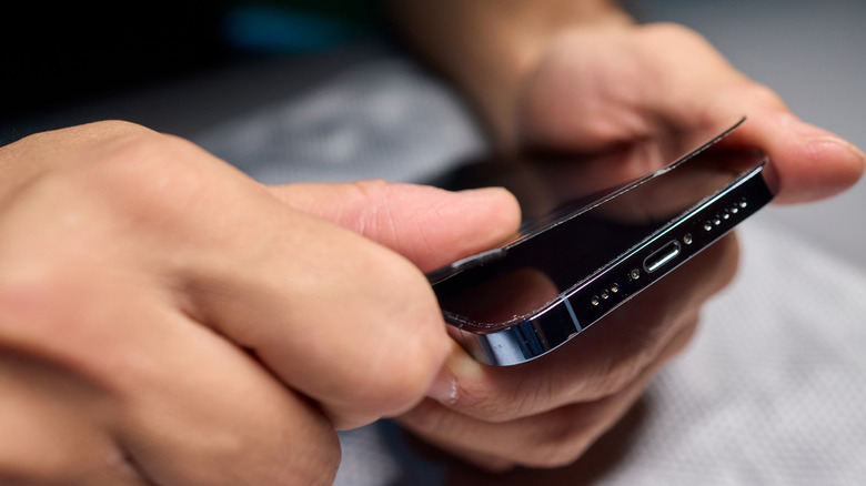 Close-up of hands applying screen protector to phone