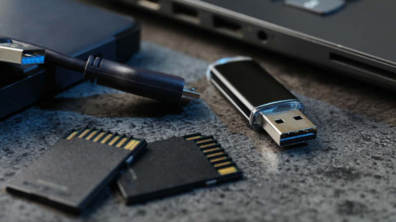 A USB drive and SD cards in front of a computer