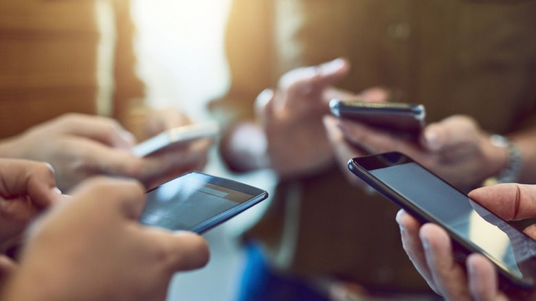 Close up of four sets of hands using smartphones