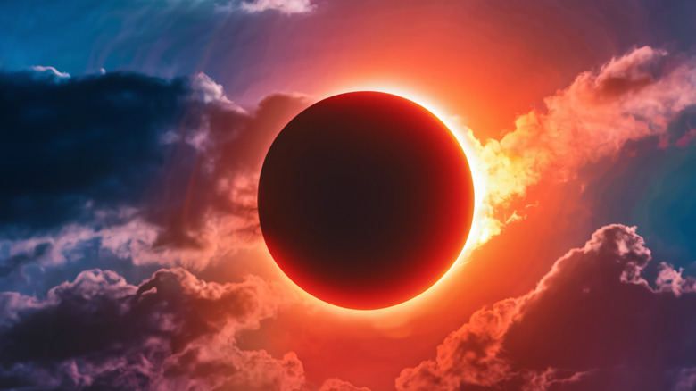 A stunning photograph of a solar eclipse taking place during the afternoon sky. The sun is mostly obscured by the moon.