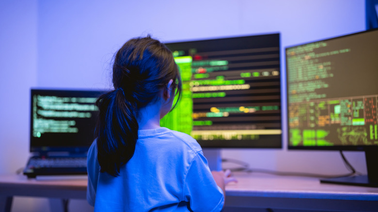Young girl in front of multi-monitor desktop setup.