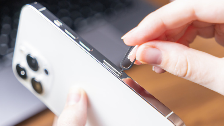 Close-up of a person inserting a SIM ejector tool into a phone