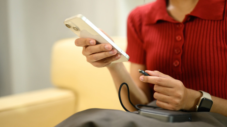 A woman plugging a power bank into a phone
