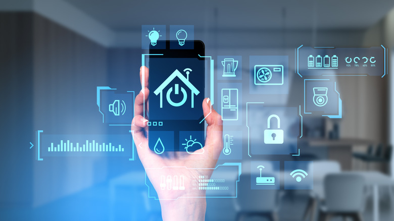 Person's hand holding a smartphone with smart home IoT icons and data represented over the phone