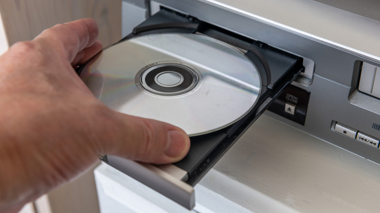 A man placing a disc in a DVD player