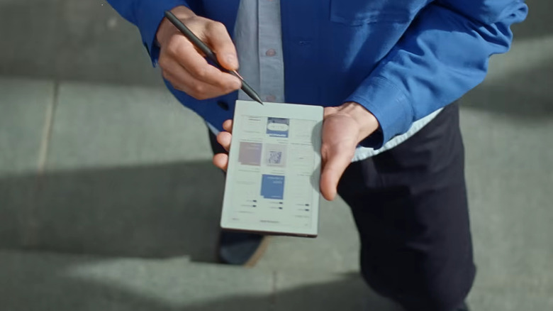 A man in a blue jacket draws on a reMarkable color tablet.