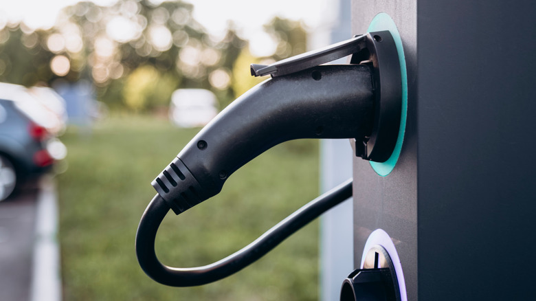 A closeup of a vehicle charging plug still attached to its charging station