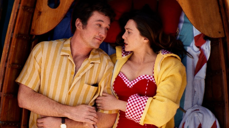 Larry and Joan lying while looking at each other in a boat