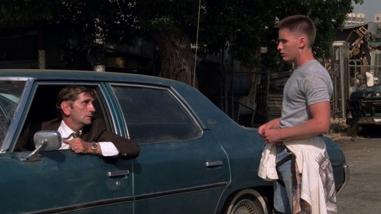 Bud (Harry Dean Stanton) sitting in a car while Otto (Emilio Estevez) stands outside.