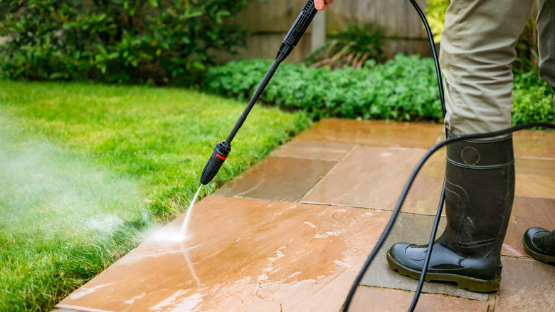 Man in boots power washing his patio