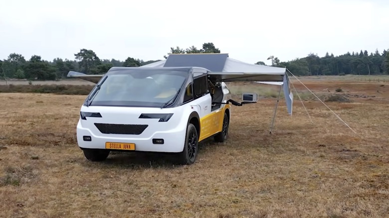 Solar Team Eindhoven's solar-powered ambulance parked in a field with its wing-like arrays extended.