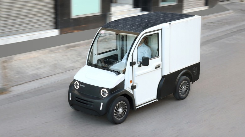 A person driving a Bako Motors solar-powered delivery van along a street.