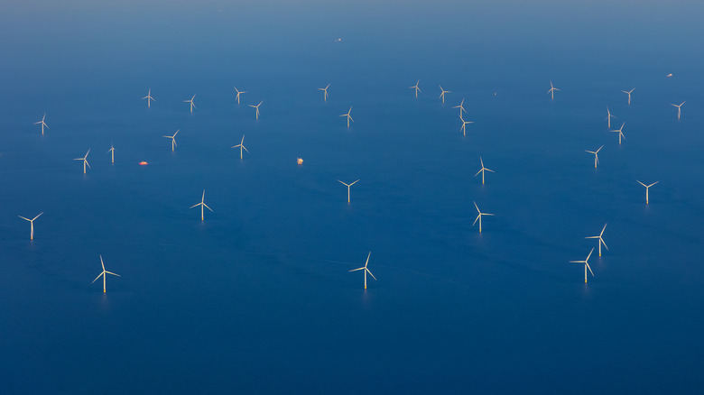 Aerial view of an expansive offshore wind farm with cargo ships navigating the waters of the North Sea.