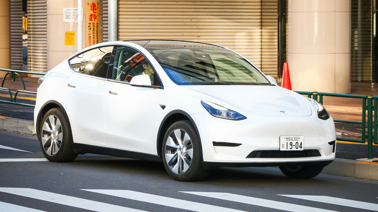 White Tesla Model Y driving on a city street.