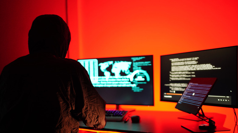 hacker working on computers in mysterious room