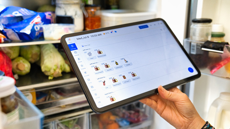 Everblog FridgeCal being held in front of an open fridge showing contents management