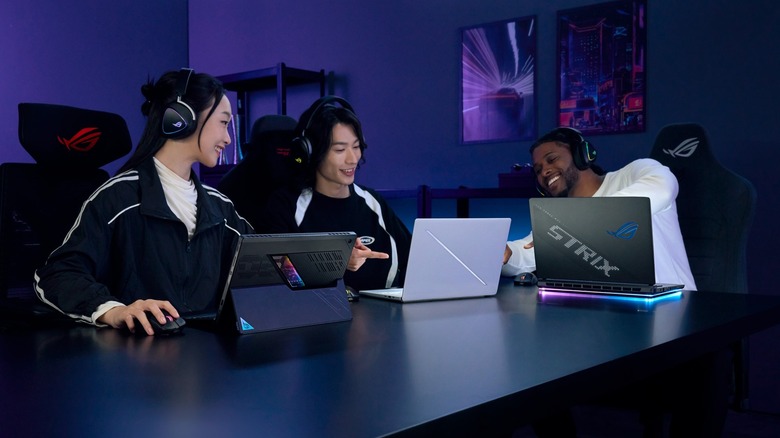 Group of people each using Asus gaming laptops and laughing together.
