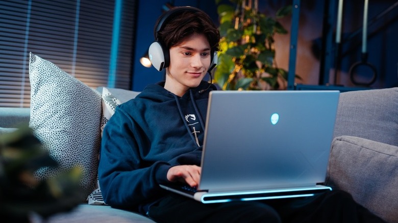 Young man using Dell Alienware on a couch.
