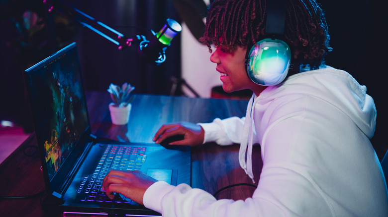 Teenager enjoying games on his gaming laptop.