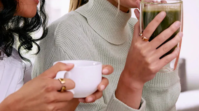 A pair of Evie Rings on the side of women's fingers while they have a drink