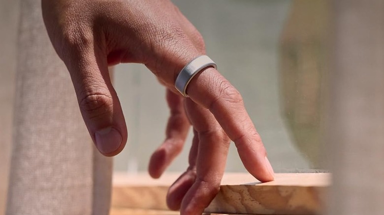 Oura smart ring on a person's finger as they touch a windowsill