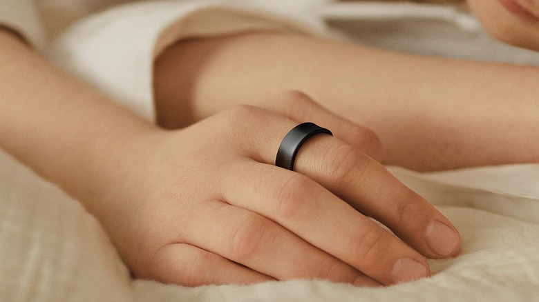 Samsung Galaxy Ring on a person's finger as they lay down on a bed