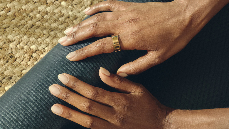 Ultrahuman Smart Ring on a person's side, above a yoga mat