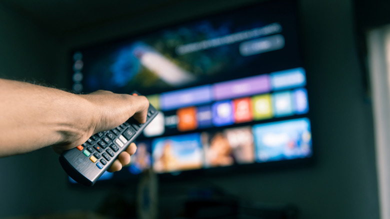 Man holding a remote pointing it towards a smart TV