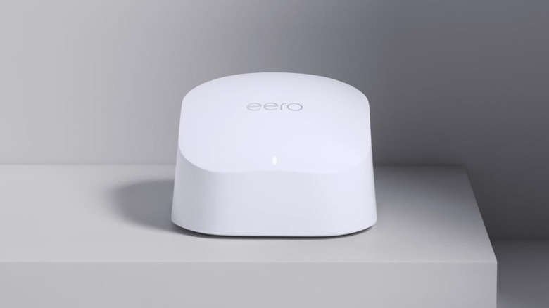 Amazon eero Wi-Fi mesh unit on a gray shelf with a gray background