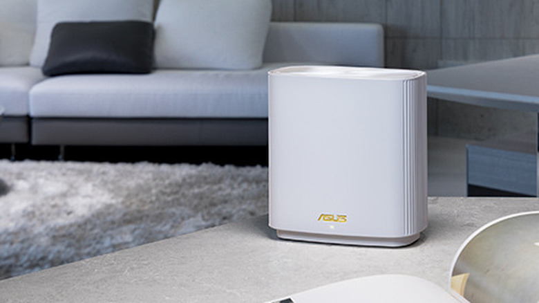 An ASUS ZenWiFi AX6600 (XT8) Wi-Fi Mesh unit on a table in a living room with a white sofa in the background