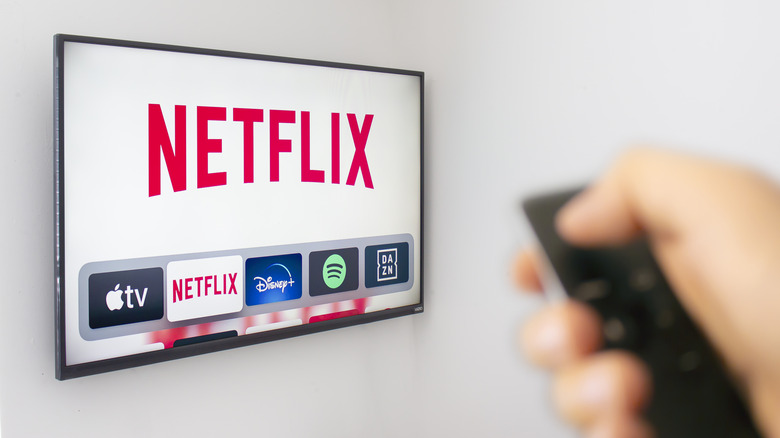 Person aiming remote at TV displaying Netflix logo