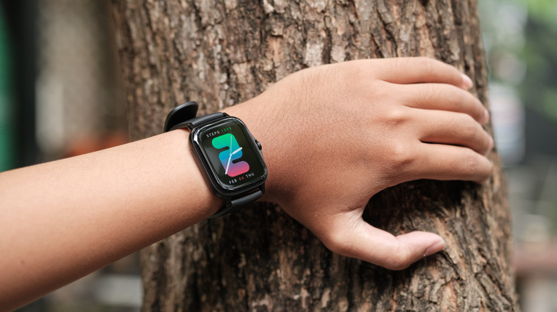 Person holding hand against tree while wearing Amazfit smartwatch