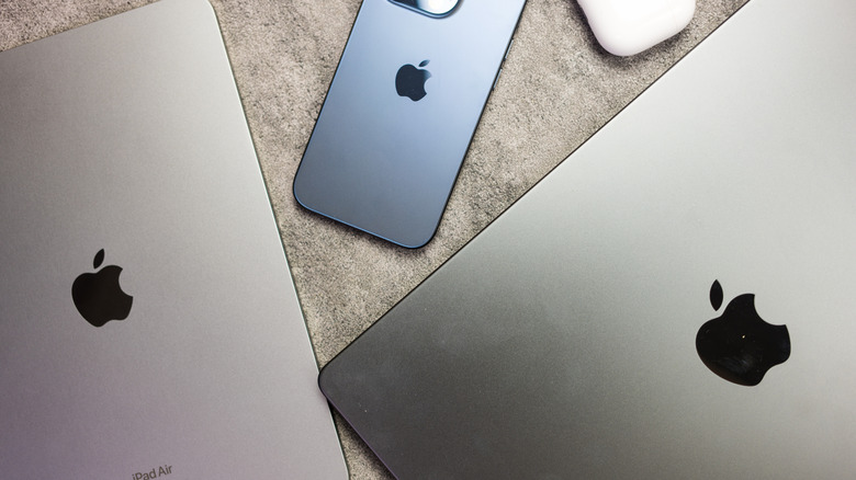 Variou Apple products on a desk, with Apple logos visible: iPad, iPhone, and Mac.