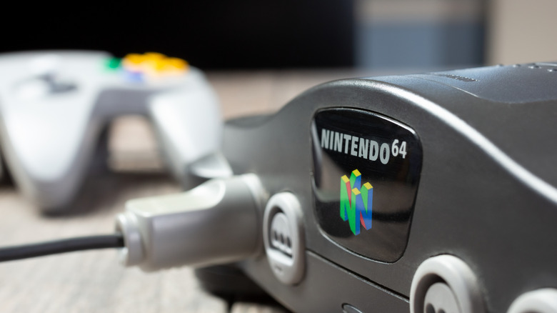 A close-up photo of the Nintendo 64, with a focus on its logo and an N64 controller in the background