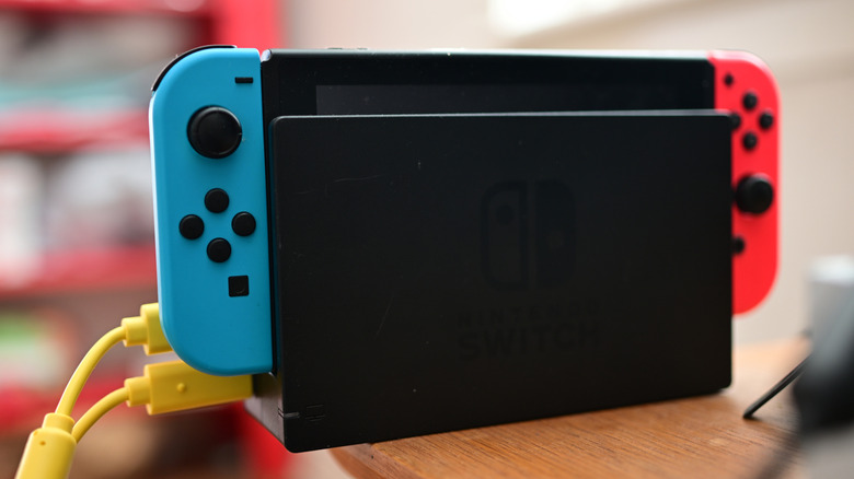 The Nintendo Switch console, docked and placed on the edge of a wooden table
