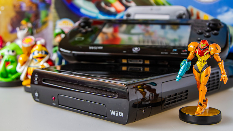 The Wii U console and the gamepad on a table full of miniatures from Nintendo games