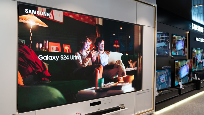 A Samsung TV displaying an ad for the Samsung Galaxy S24 Ultra, the television appears to be sitting in the media room of a big box retailer