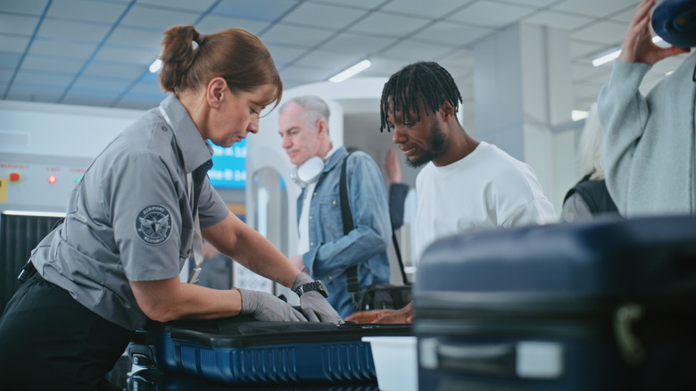 TSA security personnel checking luggage for prohibited items.