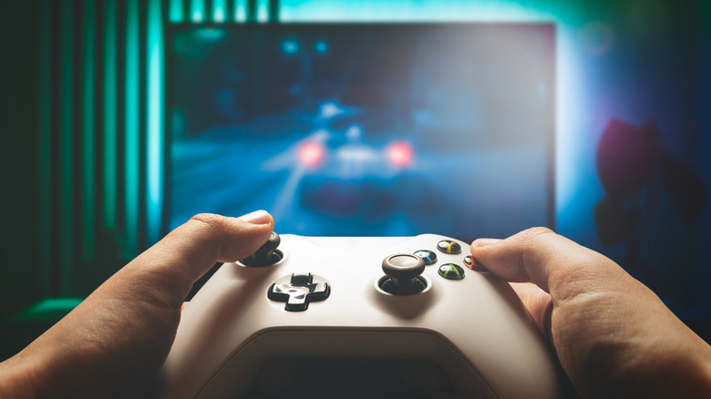 a person holding an Xbox controller in front of a TV