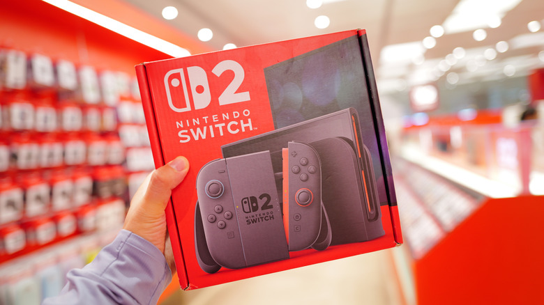 Person holding a Nintendo Switch 2 retail box inside an electronics store