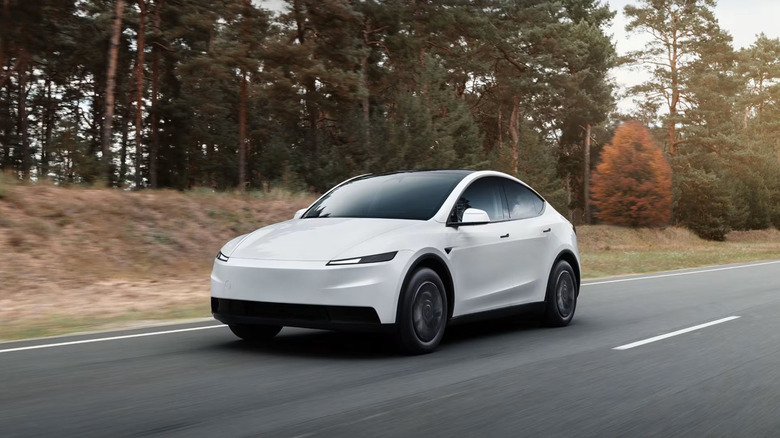 A white Tesla Model Y driving on the highway.