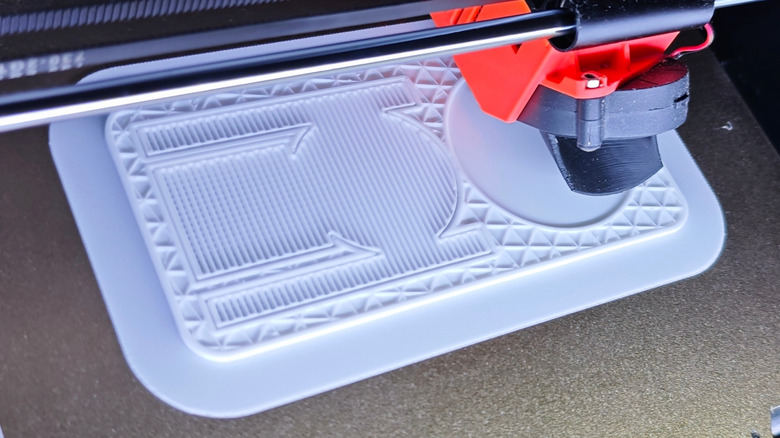 A 3D printer creating a flat surface with various patterns.
