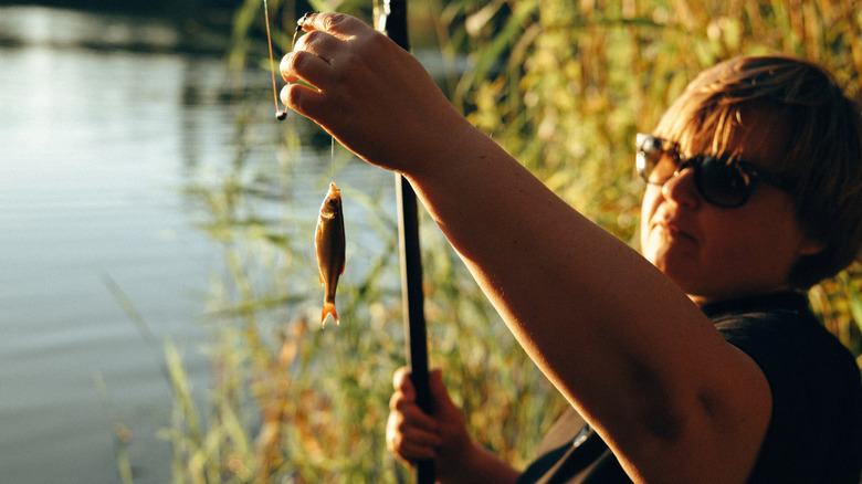 Person displaying a small fish