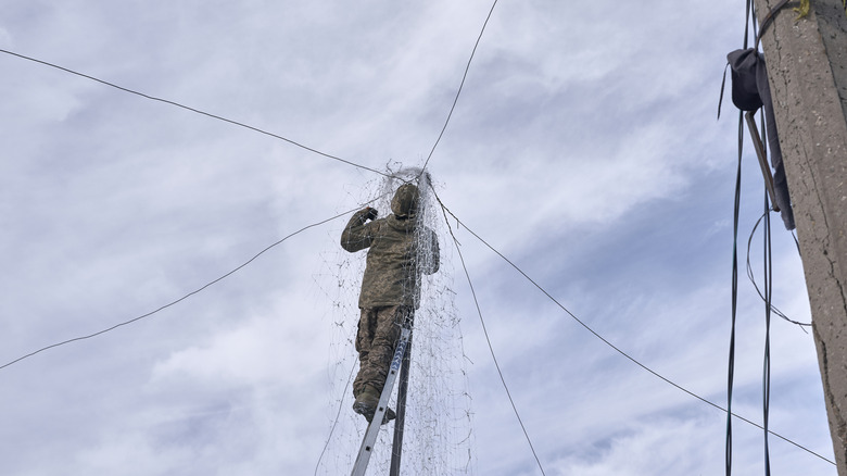 Solider installing anti-drone netting in Ukraine