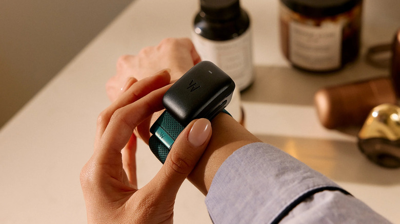 A person wearing and charging a Whoop fitness band