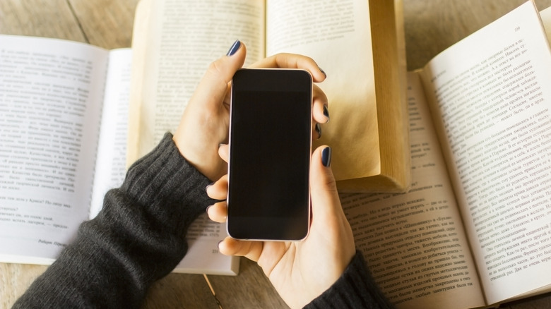 A picture of someone holding a phone over several open books