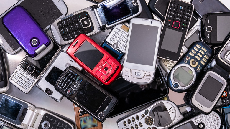 A spread of dozens of flip phones and feature phones viewed from above.