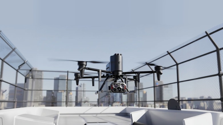 A Flock Alpha drone hovers above a building rooftop with a cityscape in the background.