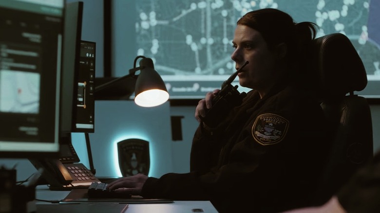 A female enforcement officer looks looks at a FlockOS crime center module in a dark room.
