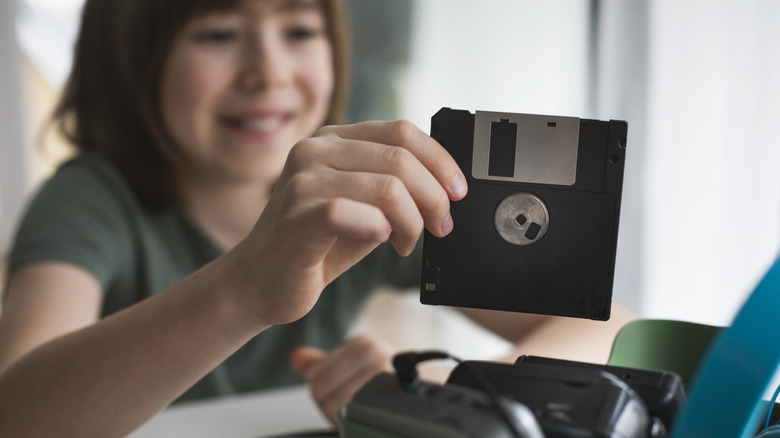 Smiling child handling a 3.5 inch floppy disk